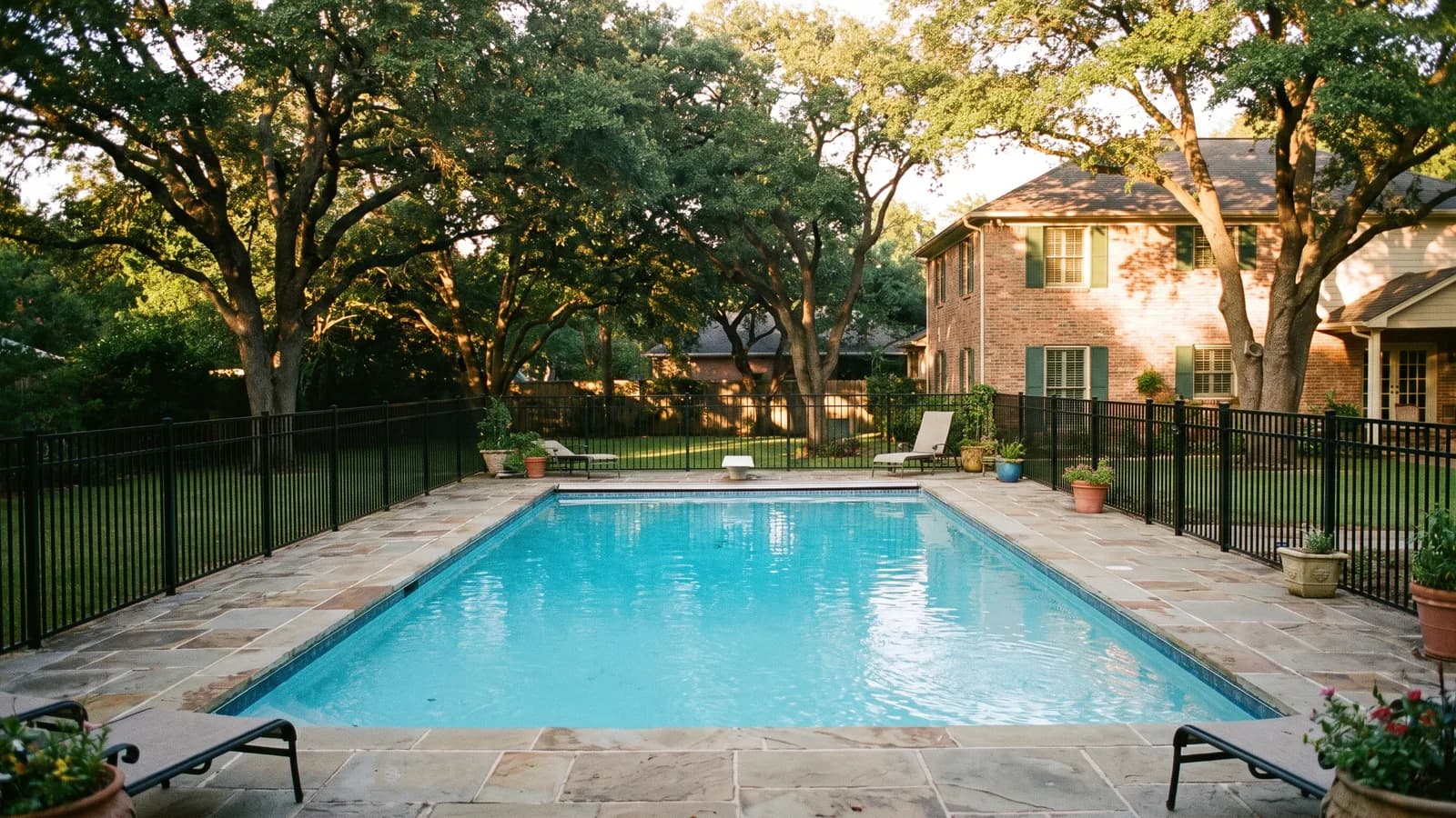 An in-ground residential swimming pool enclosed by a safety barrier fence in a Georgia back yard