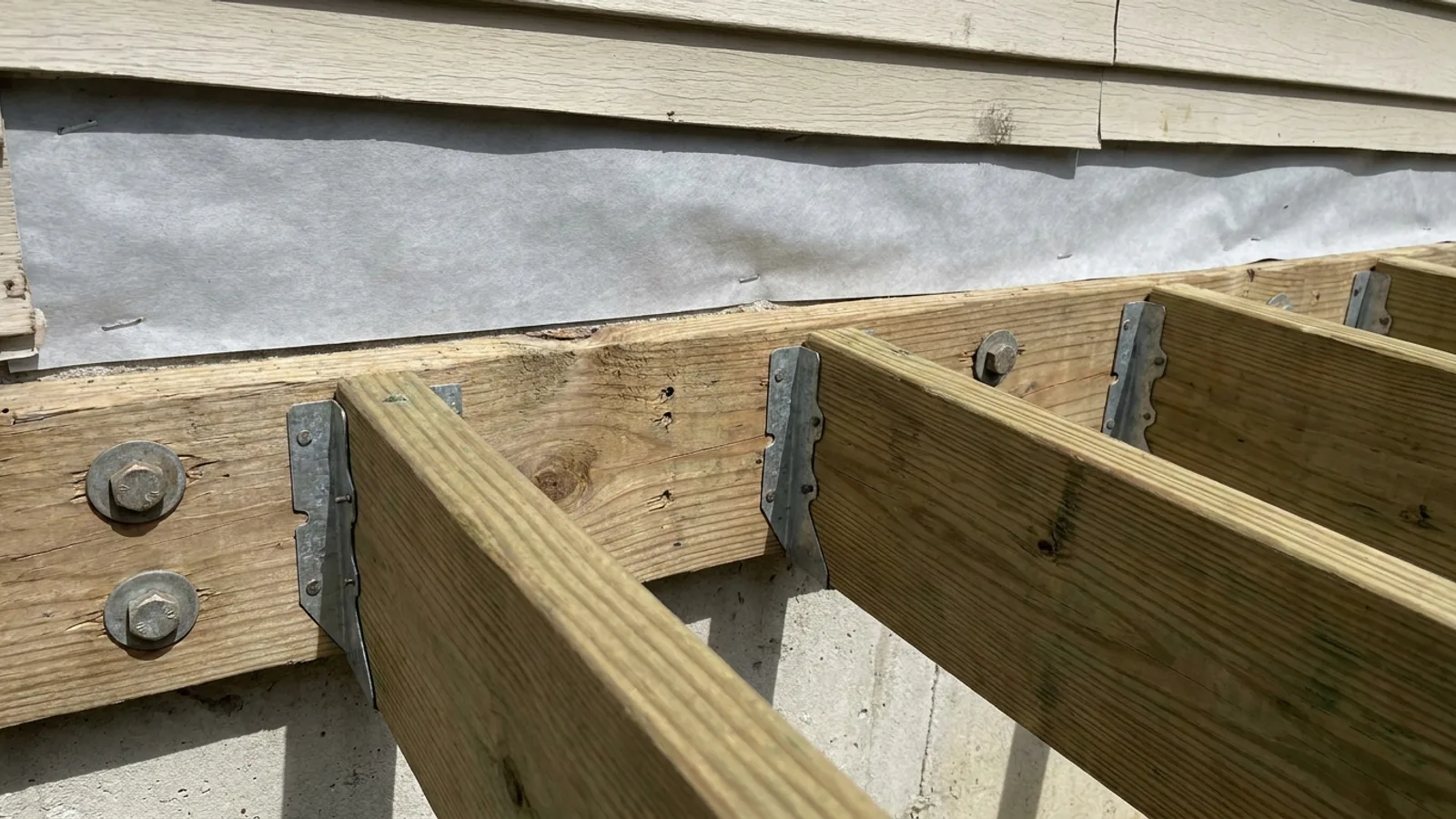 A newly built wooden deck attached to the back of a suburban home with railings installed