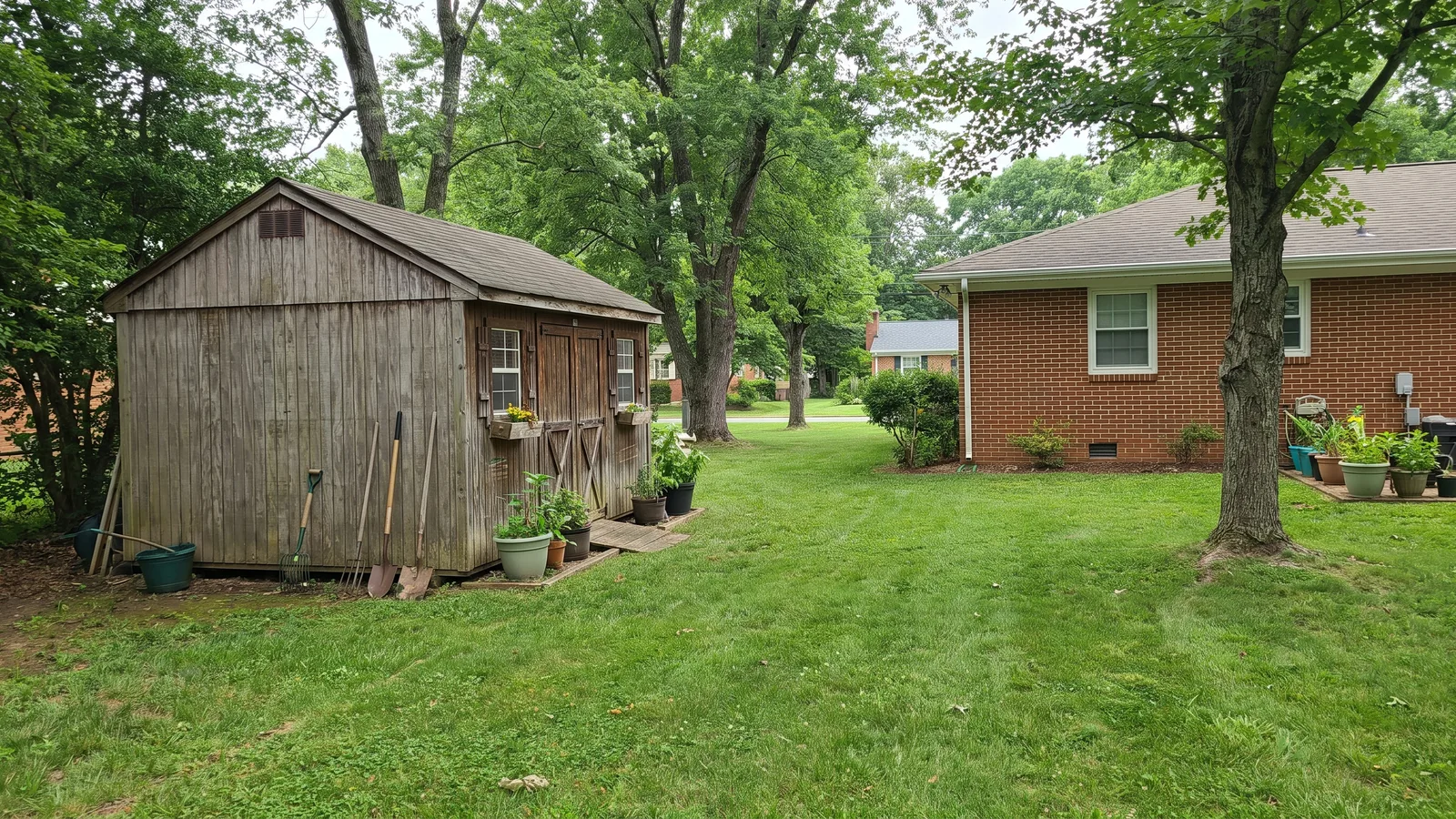 A small detached backyard accessory building beside a Virginia suburban house