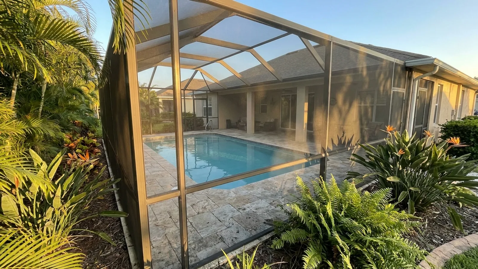 A screened pool enclosure attached to a Florida home with a rectangular pool inside