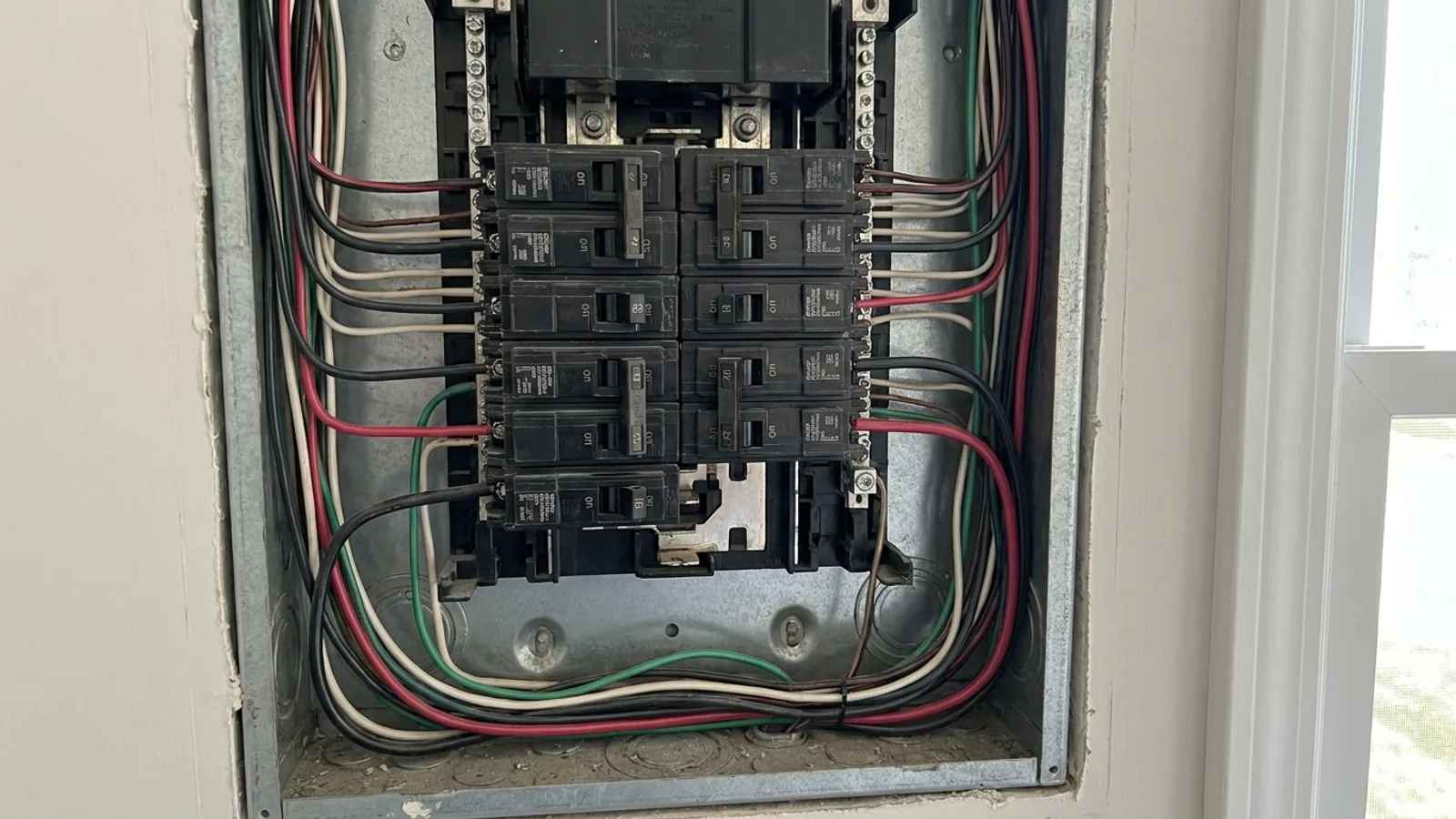 An open residential electrical panel with breakers and neatly routed wiring